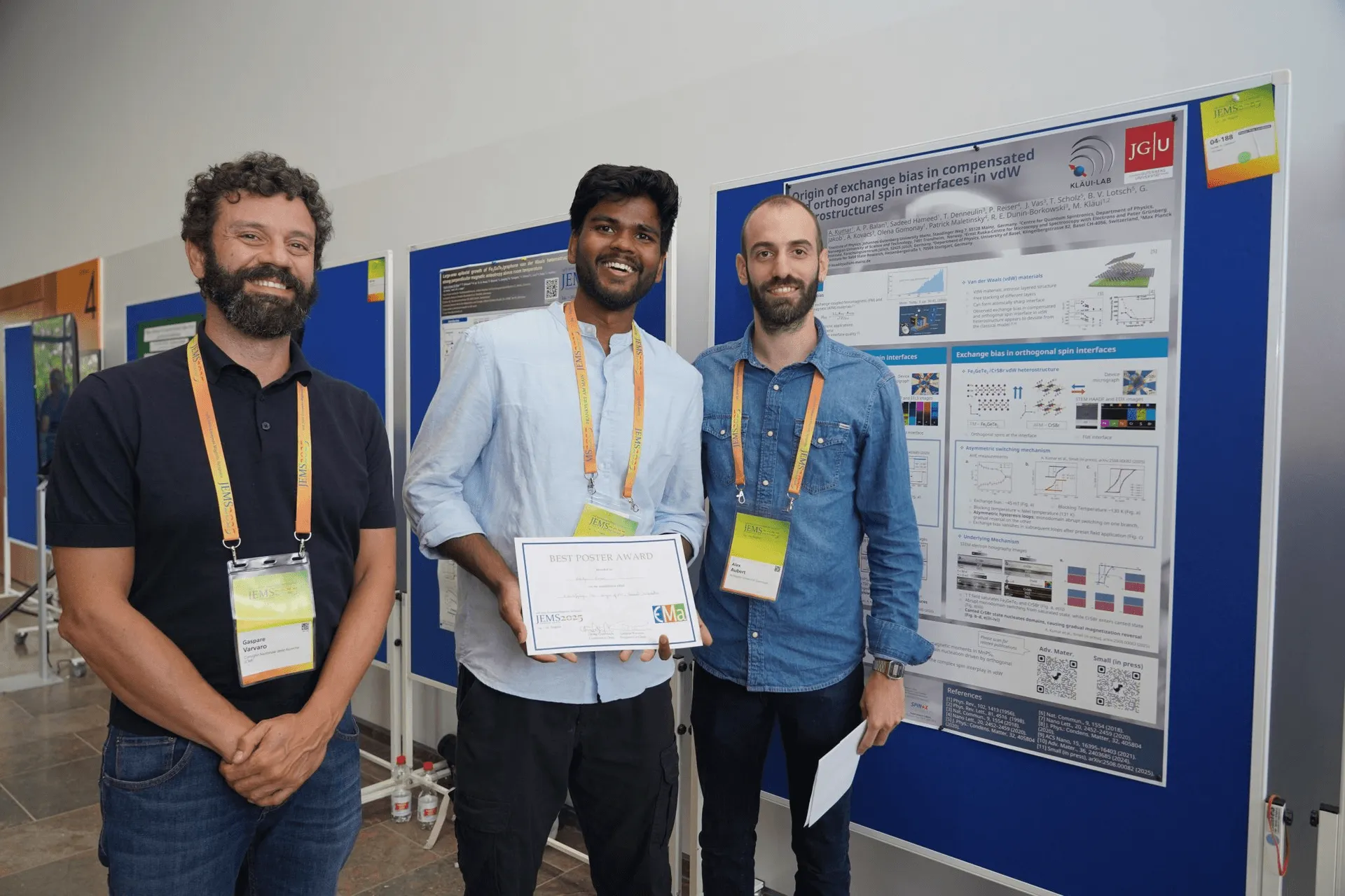 Aditya Kumar and eight other researchers holding best-poster-award certificates on stage, in front of a screen listing the winning posters.